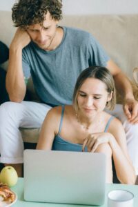 A couple sitting on a sofa browsing a laptop, showcasing online shopping leisure.